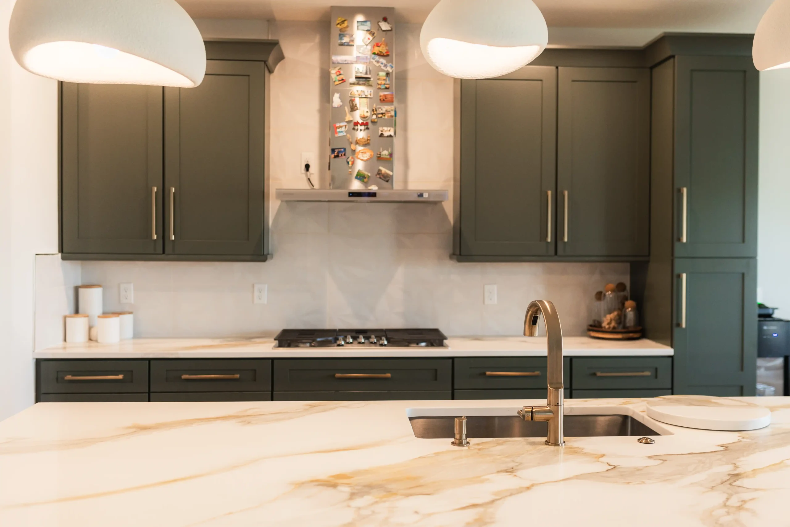 Calacatta-look quartz island with an undermount sink, set against deep green shaker cabinets